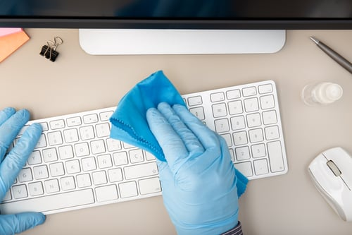 Cleaning technician wiping down an office workstation